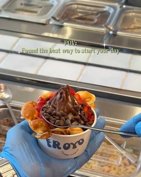 A waffle froyo with chocolate chips held over the toppings bar