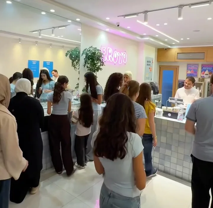 Customers queueing at the tiled Froyo counter under the pink neon sign