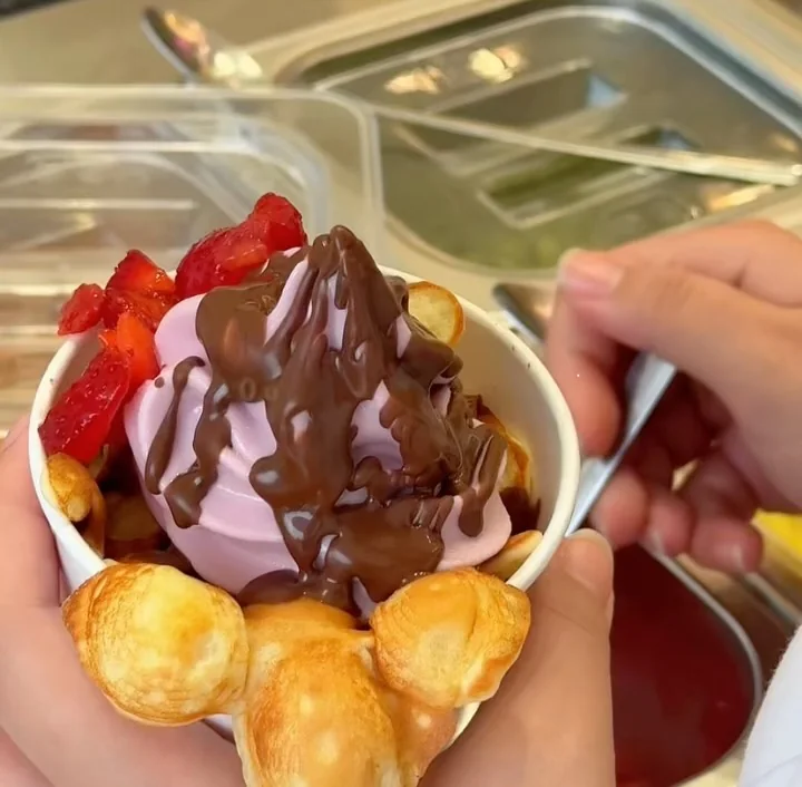 Froyo in a bubble waffle cup with strawberries and chocolate sauce
